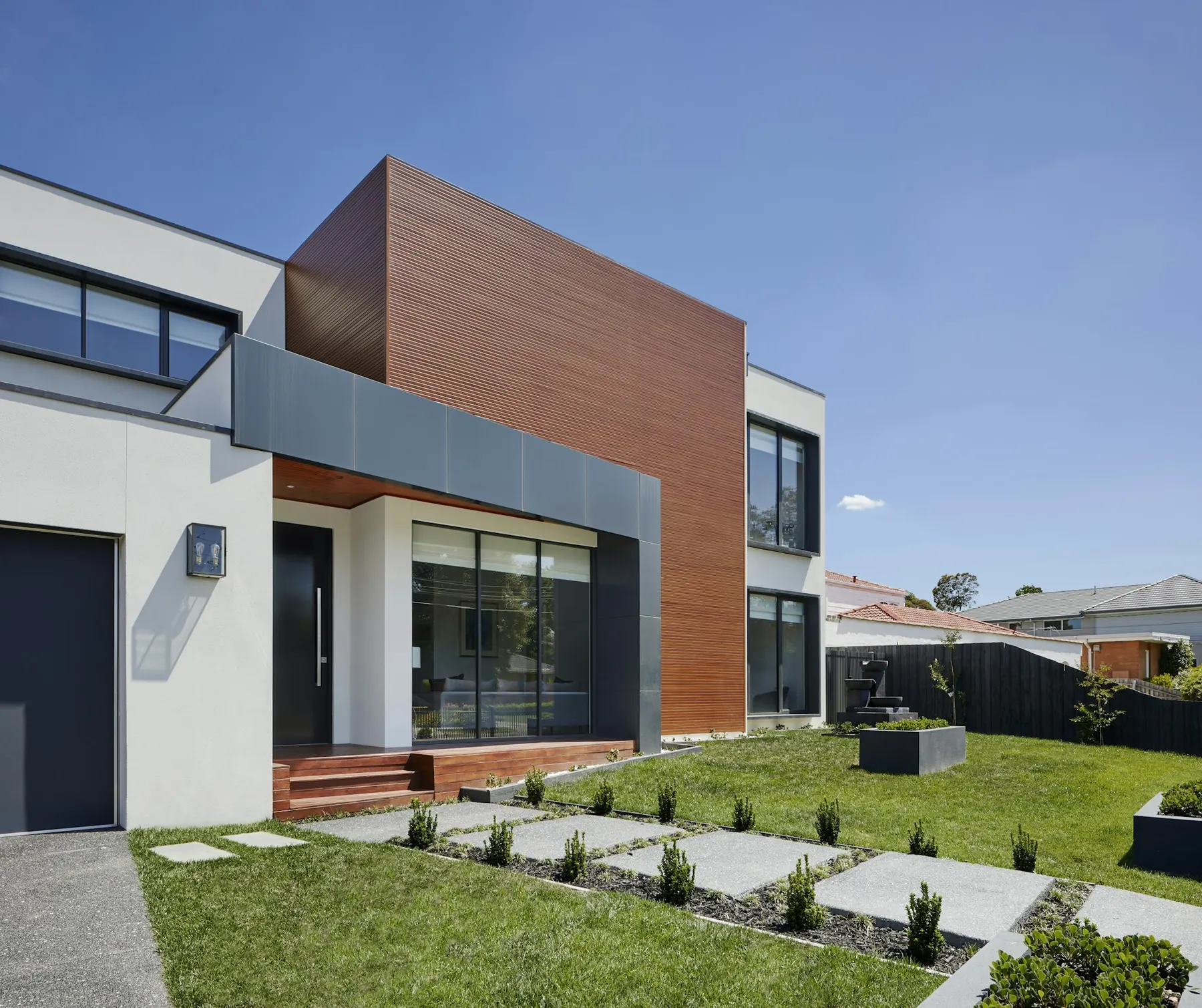 Modern two-storey house with timber-clad façade and front lawn