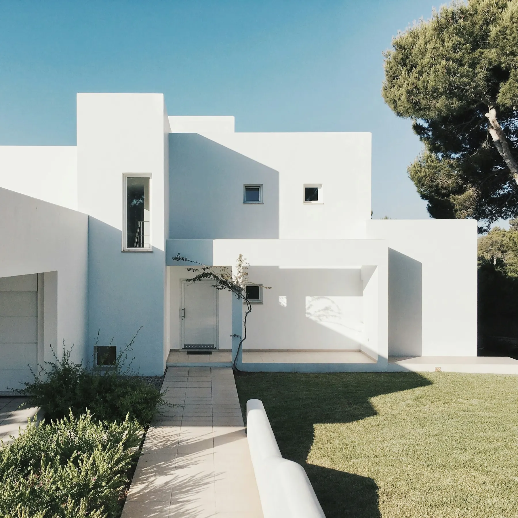 White cubic house with a small lawn